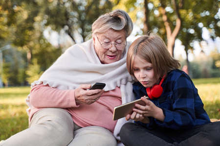 Boy showing something to his granny at his smartphone