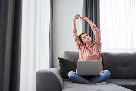 Girl sitting at the sofa with computer on her laps