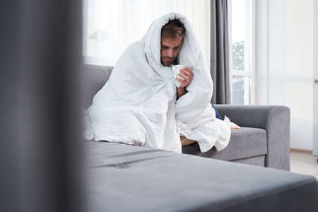 Man feeling cold while sitting on sofa