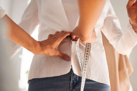 Seamstress looking at the clients back while measuring