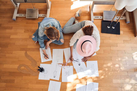 Designer and her assistant sketching on the floorの写真素材