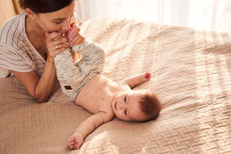 Woman kissing legs of her newborn baby
