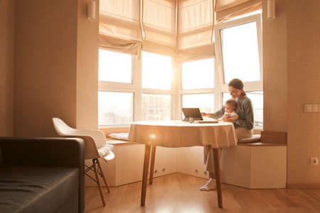 Mother sitting at the table with her newbornの写真素材
