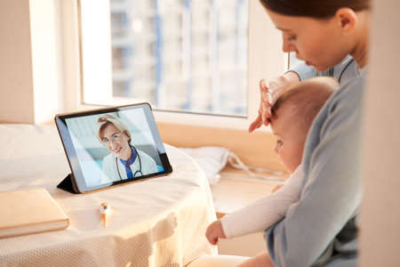 Mother measuring temperature of her babyの写真素材