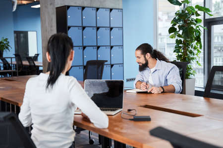 Businessman in shirt is sitting at table and taking some notes