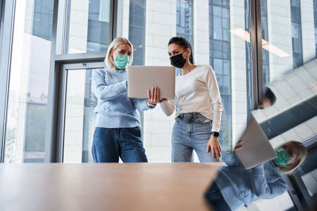 Women talking and smiling while standing in the officeの写真素材