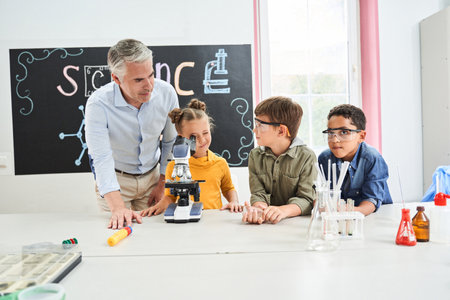 Handsome grey haired teacher speaking with pupilsの写真素材