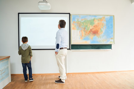 Little dark-haired boy standing near the interactive whiteboardの写真素材
