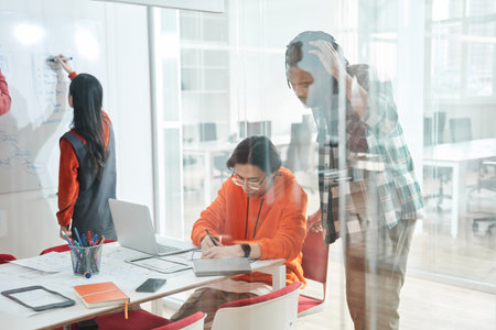 Multicultural diverse young people gather at table in classroom and discussing assignmentの写真素材