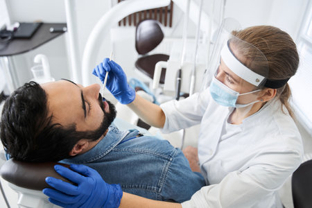 Confident woman dentist at work with her male patientの写真素材