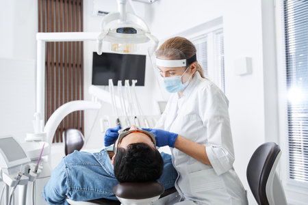 Friendly dentist adjusting something while working in dental clinicの写真素材