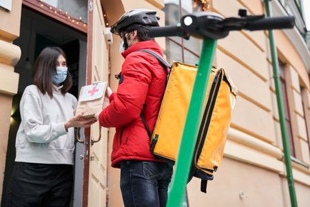 Delivery man standing at the street and holding package with medicamentsの写真素材