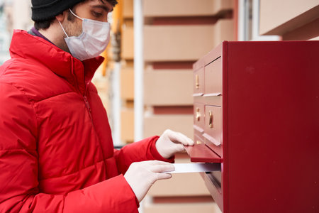 Man carrying packages while delivering mail in mailboxの写真素材