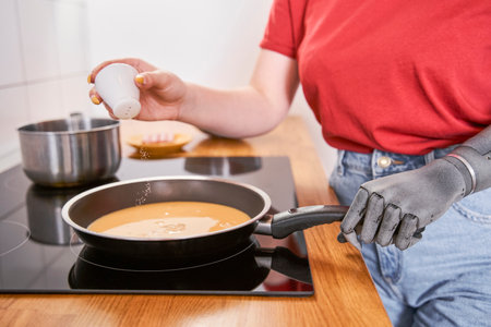 Woman with prosthesis hand frying omelet at the panの写真素材
