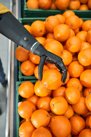 Woman with prosthesis arm standing with orange in handの写真素材