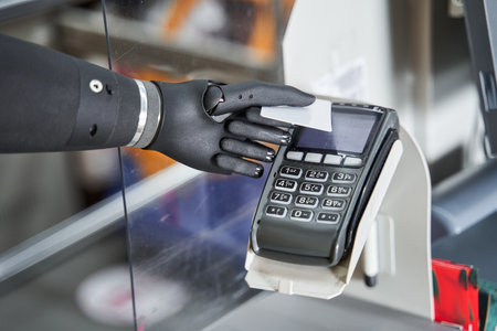 Woman with prosthesis arm using terminal and paying for shoppingの写真素材