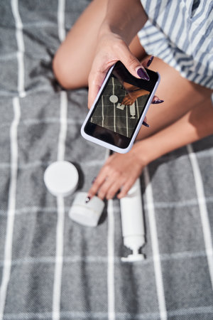 Woman making photo with smartphone of bottles of cream