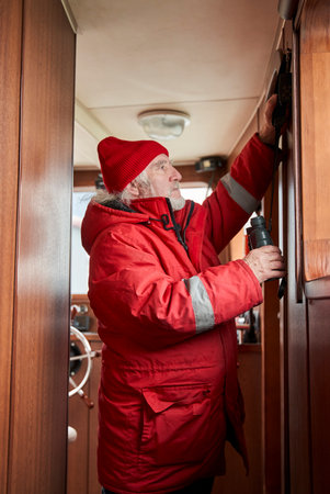 Captain with binoculars adjusting something inside of the yachtの写真素材