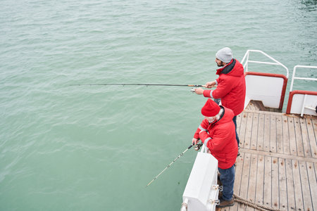 Sailor helping to the diligent fisher to taking out huge fishの写真素材