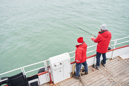 Sailor helping to the diligent fisher to taking out fish from seaの写真素材