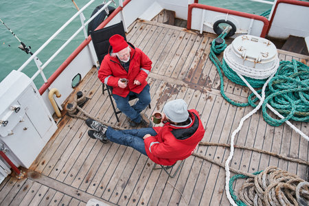 Fishermans sitting at the deck of the boat and having conversationの写真素材
