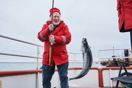 Fisherman rejoicing while holding his fish catchの写真素材