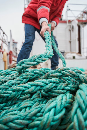 Senior fisherman pulling rope on deck of a boatの写真素材