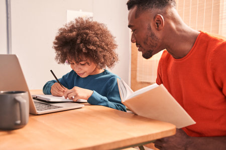 Man reading book near his son at the kitchen