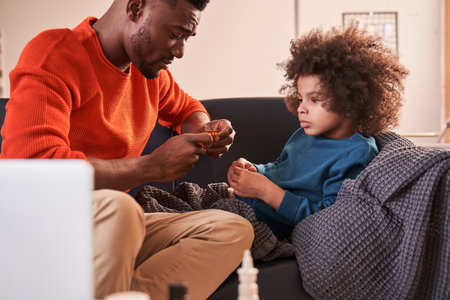 Father giving pills to his ill son at homeの写真素材