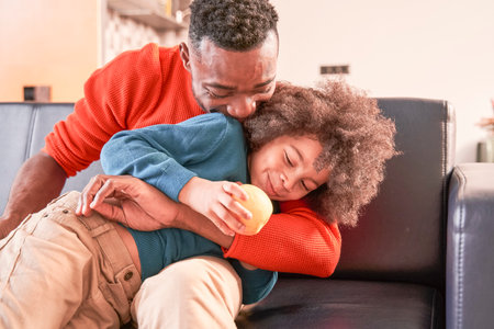 Boy sitting with his father at the sofa at homeの写真素材