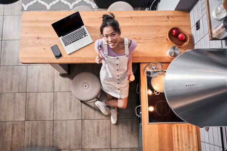 Woman standing at kitchen with a ladle spoon while eatingの写真素材