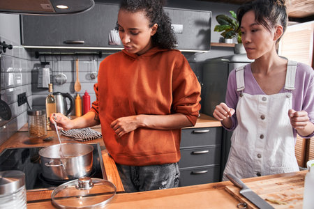 Woman carefully stirring pasta with a cooking ladle spoonの写真素材