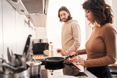 Couple cooking dinner while standing in the kitchenの写真素材
