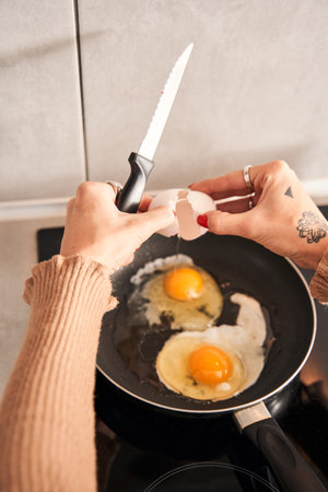 Woman preparing scrambled eggs for breakfast in kitchenの写真素材
