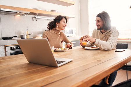 Couple having breakfast while sitting at table in a kitchenの写真素材