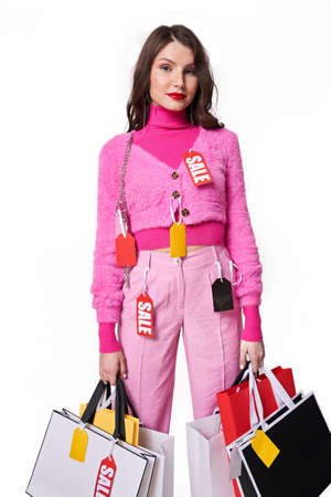 Female holding a lot of shopping bags and posing to camera