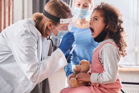 Doctor taking a cotton bud from childâs mouthの写真素材