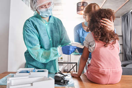 Doctor measuring temperature of girl with infrared thermometerの写真素材