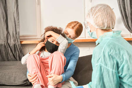 Doctor wearing protective mask chatting with patients