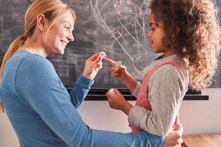Woman looking at her multiracial curly daughter with loveの写真素材