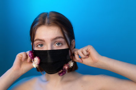Woman posing in black protective mask with flower applicationの写真素材