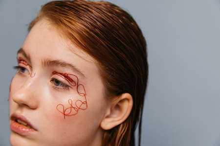 Woman without makeup with ginger hair and threads at skin