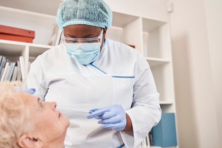 Nurse performs  virus swab on senior lady