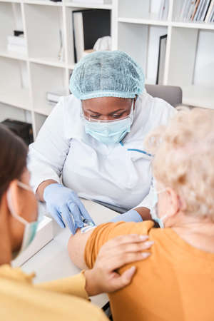 Medical worker in protective equipment carefully doing syringe