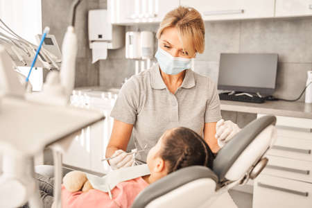Dentist examining mouth of little girl with the mirrorの写真素材