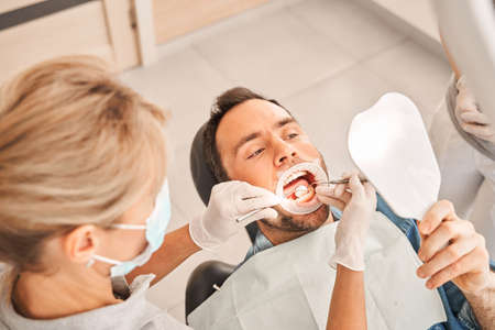 Dentist install a retractor for a male patientの写真素材