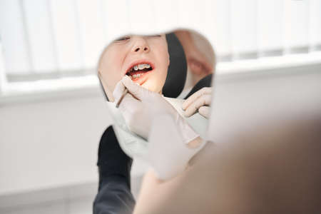 Dentist with tools in the young boys mouthの写真素材