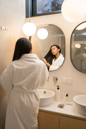 Woman combing her hairs and feeling satisfied