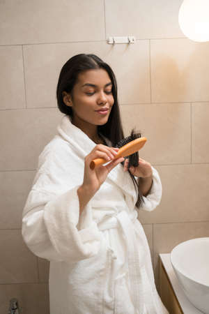 Woman checking her hair tips near mirror