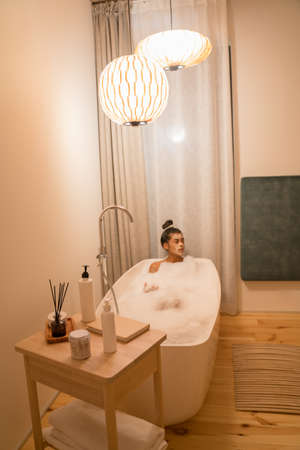 Girl is playing with foam while taking a bath